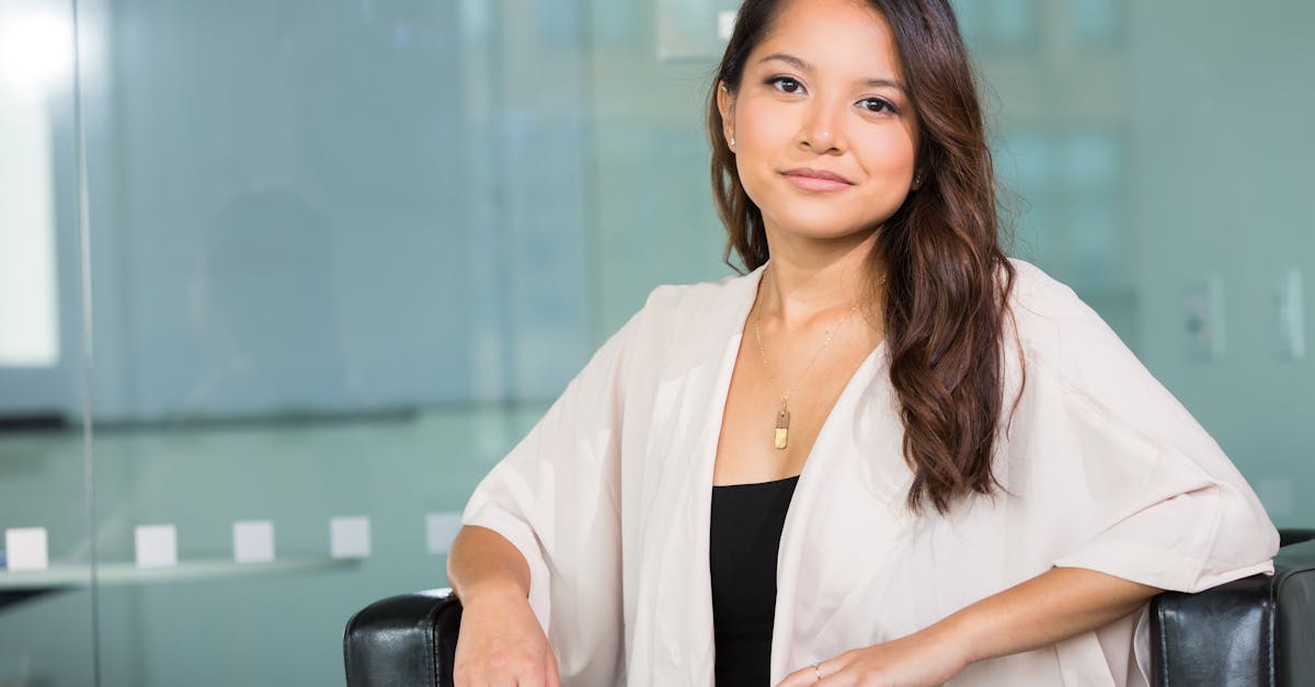 A professional Asian businesswoman sitting confidently in a modern office setting.