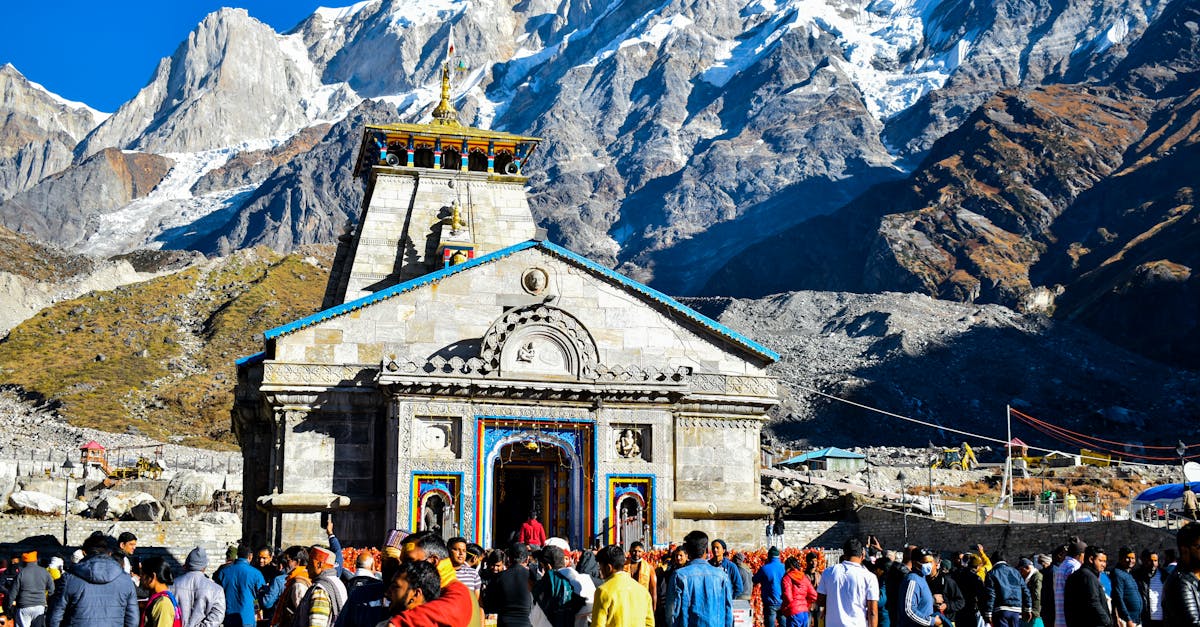 Crowd gathers at Kedarnath Temple with Himalayas backdrop, showcasing religious significance and stunning landscape.