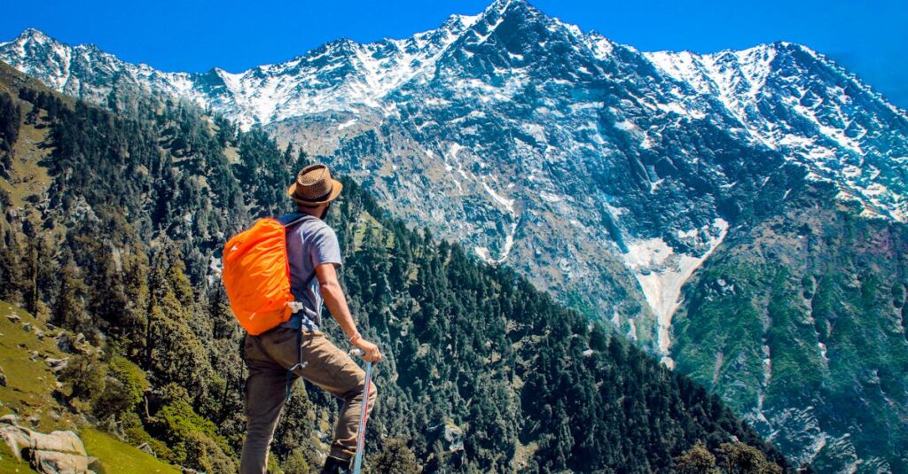 हिमालय में ट्रेकिंग: केदारनाथ और अन्य रास्तों की तैयारी | Trekking in Himalayas Guide in Hindi 1 Man exploring breathtaking mountain scenery with snow-capped peaks under a clear blue sky.