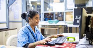 Woman in office workspace using a computer focused on work tasks.