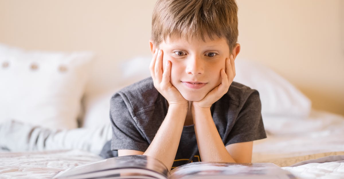 Interesting facts Young boy lying on bed, absorbed in a book, illustrating curiosity and learning.