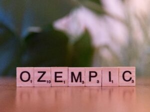 Scrabble tiles spelling 'Ozempic' on a wooden surface, healthcare theme.