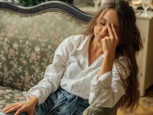 A woman relaxes on a floral vintage sofa in a cozy, light-filled room with plants. मानसिक स्वास्थ्य के लिए 10 सर्वश्रेष्ठ मेंटल हेल्थ ऐप्स: तनाव और चिंता को दूर करने के स्मार्ट तरीके
