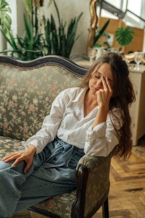A woman relaxes on a floral vintage sofa in a cozy, light-filled room with plants. मानसिक स्वास्थ्य के लिए 10 सर्वश्रेष्ठ मेंटल हेल्थ ऐप्स: तनाव और चिंता को दूर करने के स्मार्ट तरीके
