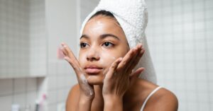 Young woman practicing skincare routine with a towel wrap indoors. दैनिक सौंदर्य रूटीन: इन 5 कोरियन DIY नुस्खों को अपने स्किनकेयर रूटीन में कैसे शामिल करें