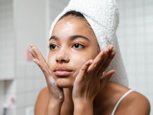 Young woman practicing skincare routine with a towel wrap indoors. दैनिक सौंदर्य रूटीन: इन 5 कोरियन DIY नुस्खों को अपने स्किनकेयर रूटीन में कैसे शामिल करें