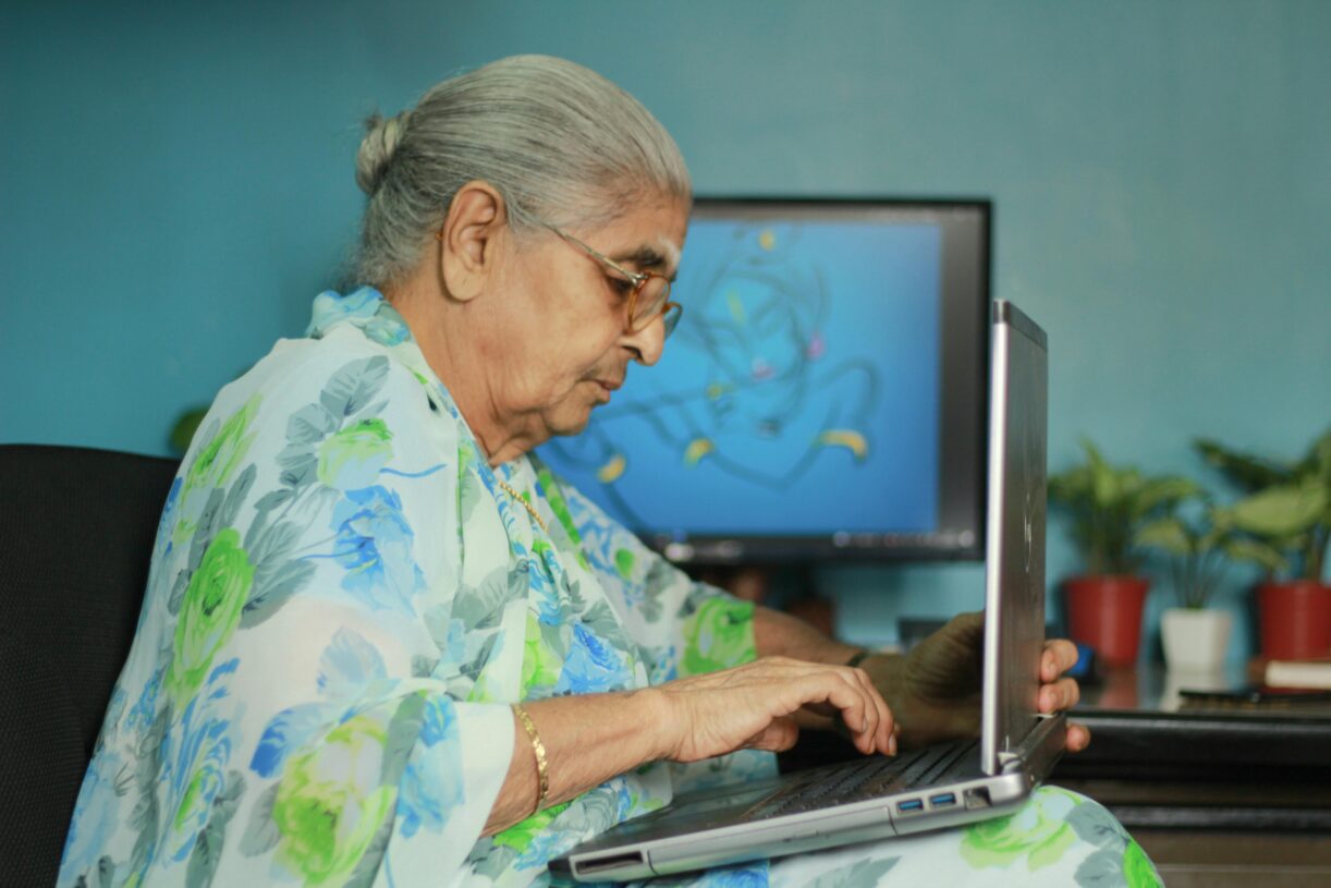 Elderly Indian woman in floral saree using a laptop at home. 2026 में महिलाओं के लिए सर्वश्रेष्ठ वर्क-फ्रॉम-होम बिजनेस आइडियाज: घर से सफलता का सफर