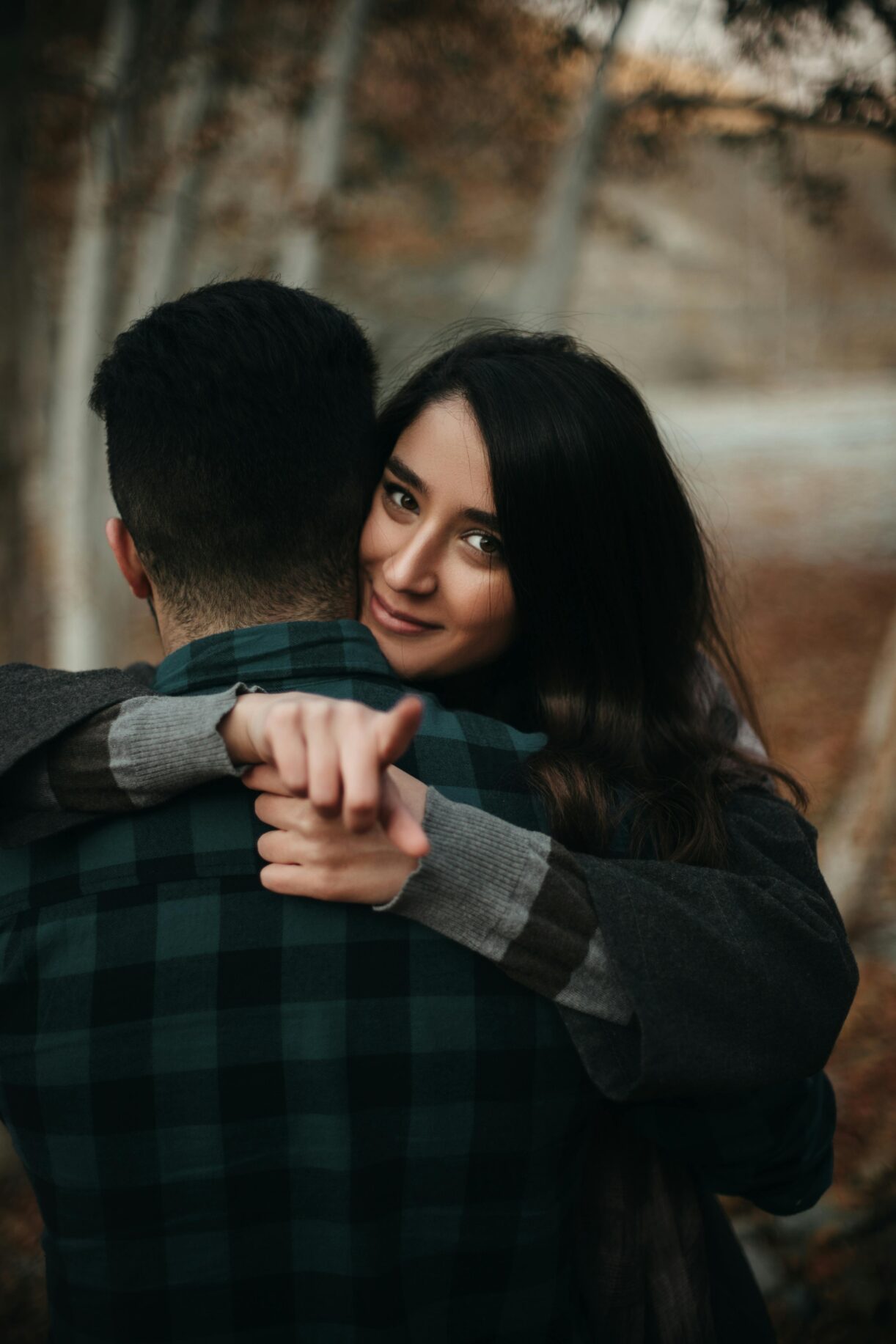 A couple embracing warmly in a London park during autumn, expressing love and togetherness.