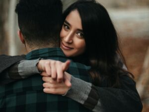 A couple embracing warmly in a London park during autumn, expressing love and togetherness.