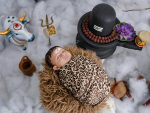 A serene baby wrapped in a leopard-print swaddle lies amidst symbolic Hindu elements.