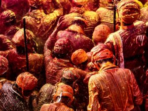 Colorful crowd celebrating Holi with vibrant powders in India.